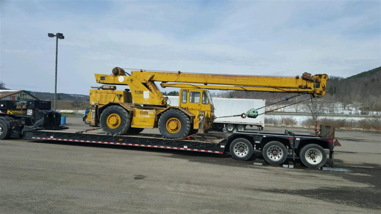 Truck crane loaded on RGN trailer for travel.