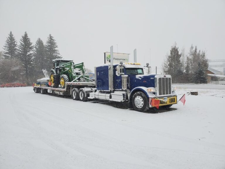 Transporting an oversize John Deere tractor in snowy conditions.