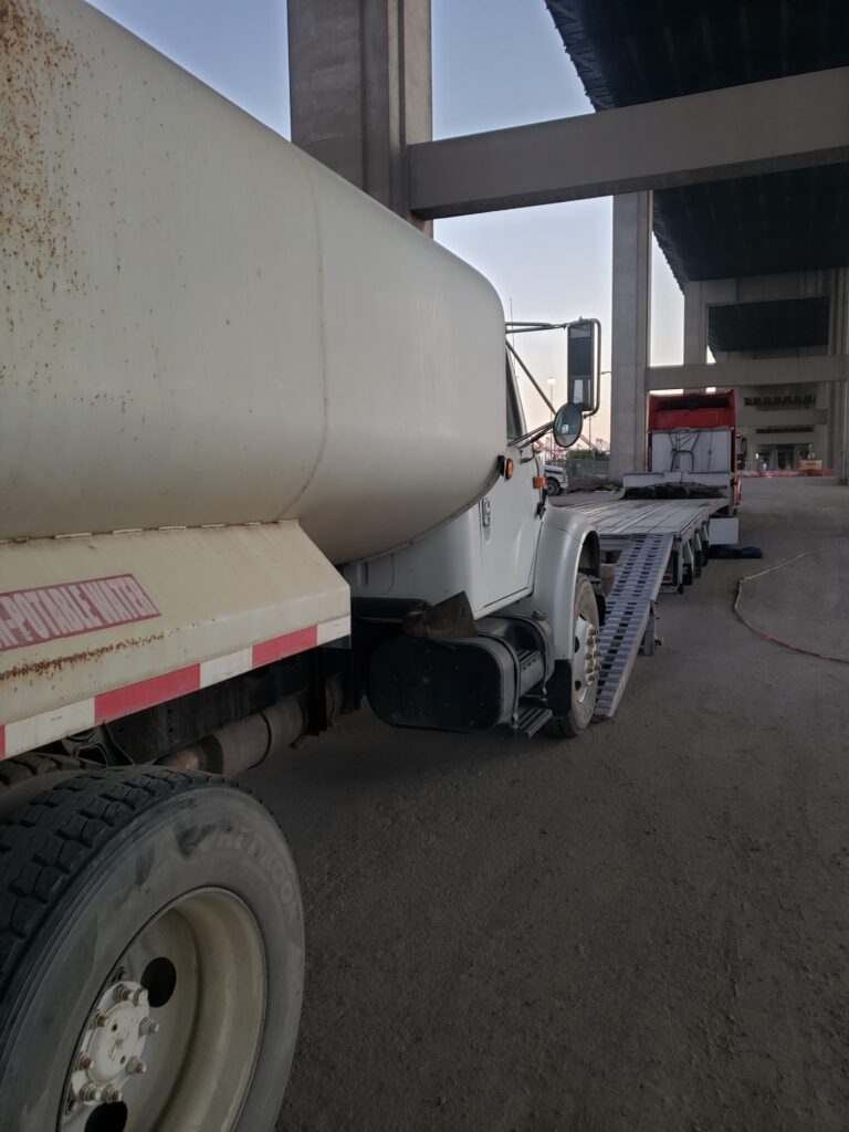 Portable water truck transported on trailer.